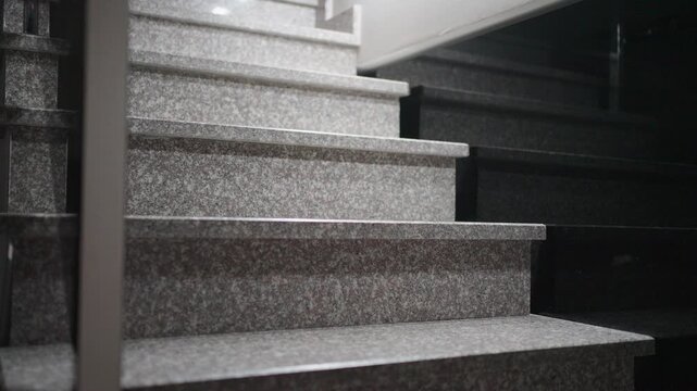 A Jack Russell Terrier climbs a stone staircase indoors. A white and brown Jack Russell Terrier carefully climbs marble steps. Concept of pet mobility and home safety.