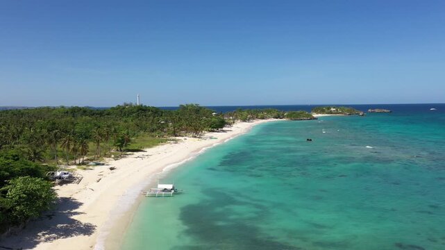 Aerial view of turquoise waters meeting white sandy beach with lush green trees, Daanbantayan, Central Visayas, Philippines.