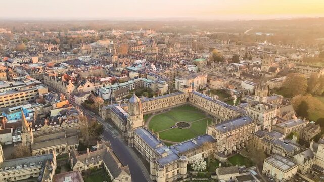 Aerial view of Oxford's ancient buildings and lush green courtyards bathed in the warm glow of sunrise, creating a striking contrast of textures, Oxford, England, United Kingdom.