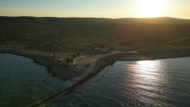 Aerial drone view of a parked campervan at beach Louri on Limnos Island, Greece. Remote Mediterranean coastal landscape with turquoise sea, rocky shoreline, and peaceful free camping atmosphere ideal