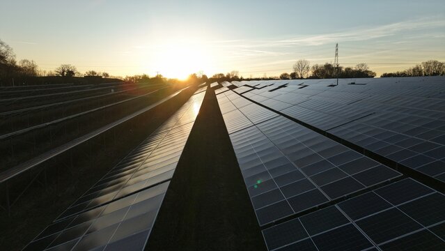 Sunset aerial view of solar panels near Ipswich UK with golden light glinting off photovoltaic cells at Tye near Ipswich