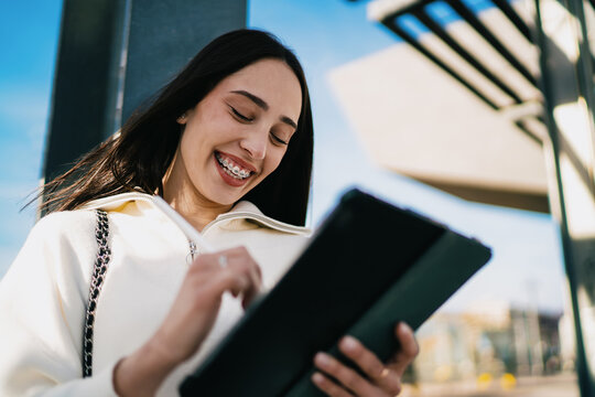 Side view of woman holding smartphone and looking away thoughtfully at bus stop, career growth, ambition, digital nomad life, urban architecture background, copy space, modern connectivity.