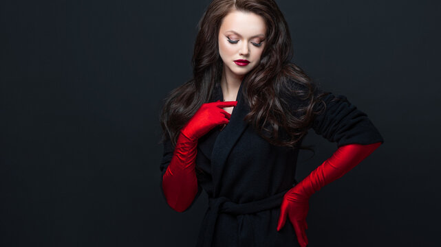 Elegant woman red gloves scarlet lips black coat
