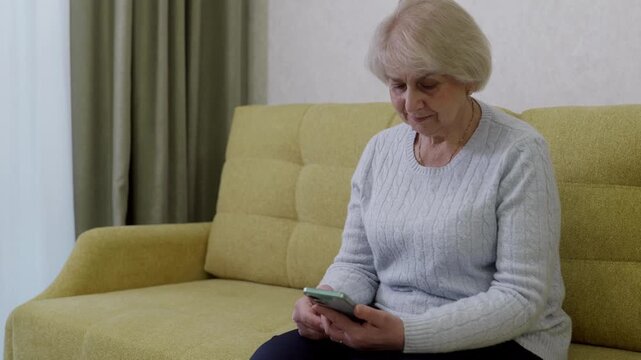 Retiree white woman holding smartphone, reading messages with thoughtful expression, adjusting settings and notifications, managing digital updates, indoor calm, senior tech moment