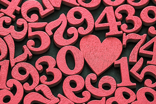 Pile of old vintage wooden red numbers and heart. Typography background composition.