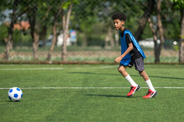 Fototapeta premium International school student practicing soccer dribbling on the field