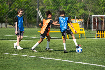 Fototapeta premium Group of international school kids playing soccer together on the field