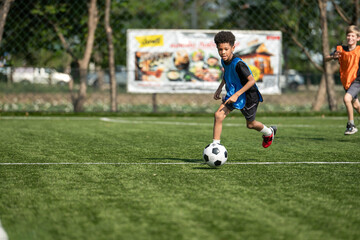 Obraz premium Group of international school kids playing soccer together on the field
