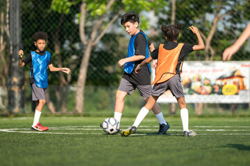 Naklejka premium Group of international school kids playing soccer together on the field