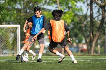 Obraz premium Group of international school kids playing soccer together on the field