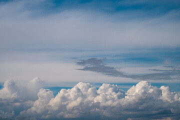 Fototapeta premium a dramatic layer of bright white, fluffy cumulus clouds at the bottom, topped by soft, wispy cirrus and grey cloud formations