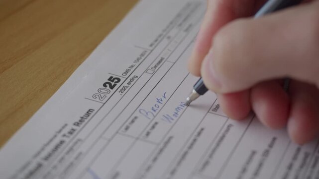 Man Filling In The Tax Form 1040. Person Calculates of Planning Budgets Yearly Personal Finance and Fills up US Tax Form 1040. Signing 1040 Income Tax Return. Names and numbers are fictitious.