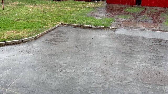 Heavy rain falling on asphalt pavement in backyard