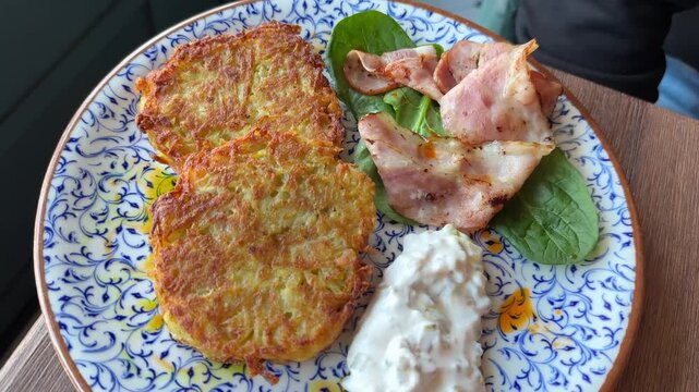 Potato pancakes with sour cream and fried bacon. Hash browns