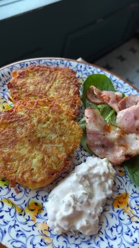 Potato pancakes with sour cream and fried bacon. Vertical. Hash browns