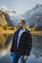 Fototapeta premium Man standing by alpine lake with mountain backdrop – outdoor lifestyle and travel concept