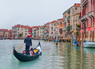 Venetian gondolier punting gondola through green canal waters of Venice, Italy © muratart