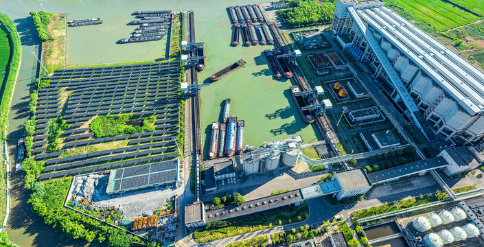 Aerial view of modern industrial port featuring solar power station, cargo barges, and logistics facilities integrating sustainable energy with waterway transport.