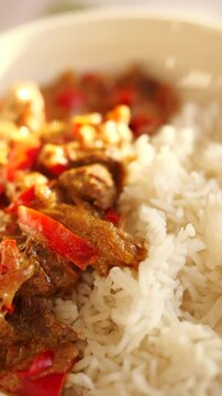 Creamy beef and red pepper stew with white rice served on a marble countertop.