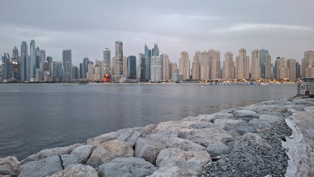 Panoramic view of Dubai Marina and JBR skyline skyscrapers from the rocky coast.