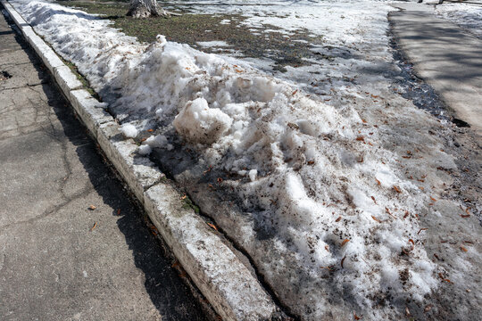 Dirty snow has been cleared to the side of the asphalt road