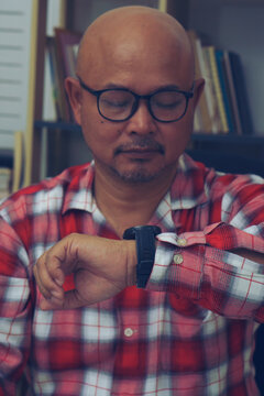 Businessman checking time and looking at smart wrist watch at home office.  Asian man seeing clock to work. Desk with laptop, annual, and summary report.Time out for appointment meeting concept.