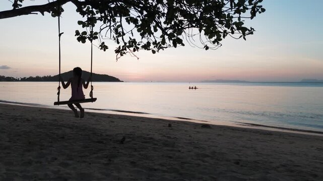 Girl swinging on beach koh samui at sunset