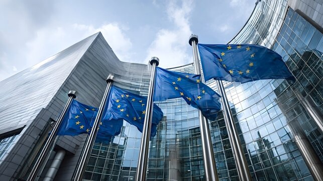 European union flags waving in a row against a modern glass parliament building, symbolizing european unity, politics, and international cooperation in brussels