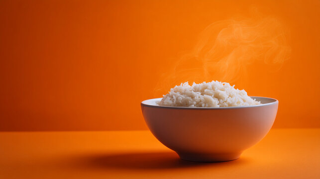 Steaming bowl of white rice on orange background