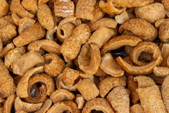Full frame top view of golden, crunchy fried pork rinds or cracklings. Popular traditional snack known as chicharrones or torreznos in Spanish cuisine.