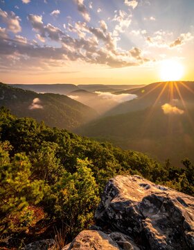 Hilly landscape at sunset with sunburst and dramatic clouds from rocky overlook