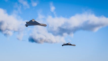 3d render of Shahed style one-way attack drones in front of blue sky with clouds. Selective focus on closest drone © Andreas Prott
