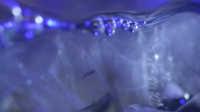 Ice cubes falling into water with oxygen bubbles, frost patterns, and soft light reflections. Concepts for beauty advertising, menu designs for bars and restaurants, cryotherapy.