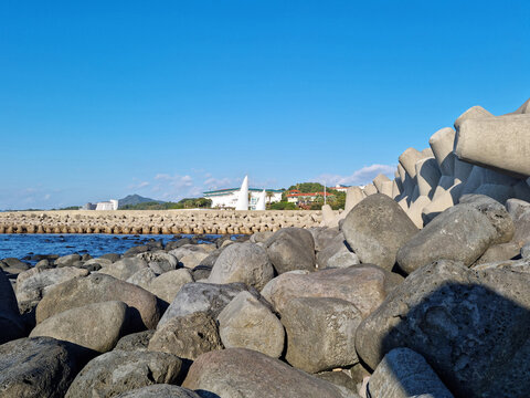 Jeju Island beach with breakwater and basalt rocks.