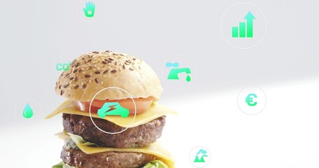 Obraz premium Presenting seeded double cheeseburger stacked on bright studio surface, showing turquoise eco icons