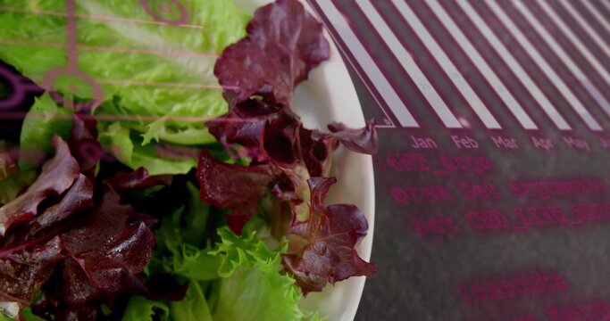 Featuring white ceramic bowl holding green burgundy lettuce mix on tabletop, with calendar placemat