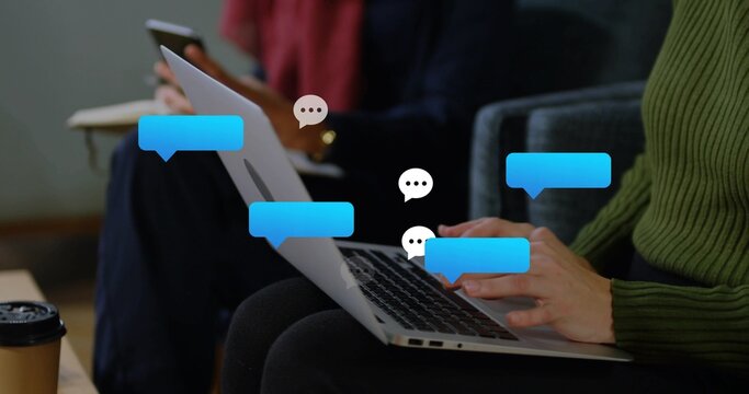 Typing woman in green sweater tapping silver laptop keys at lounge, chat bubbles floating