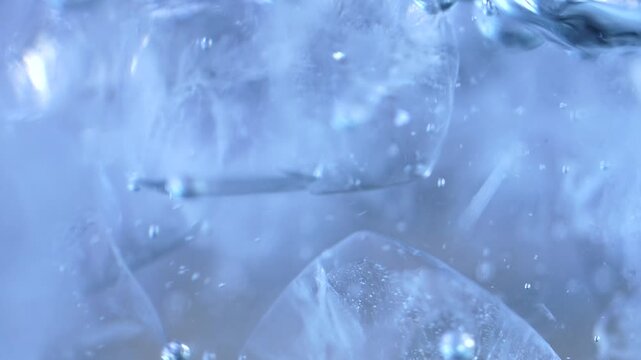 Ice cubes falling into water with oxygen bubbles, frost patterns, and soft light reflections. Concepts for beauty advertising, menu designs for bars and restaurants, cryotherapy.