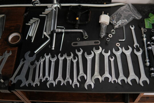 Neatly arranged wrenches, hex keys and assorted hand tools on dark workbench, ready for maintenance, repair and diy projects with chrome and steel precision