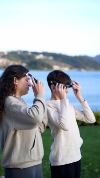 Vertical video of two teenagers observing a solar eclipse with protective glasses outdoors