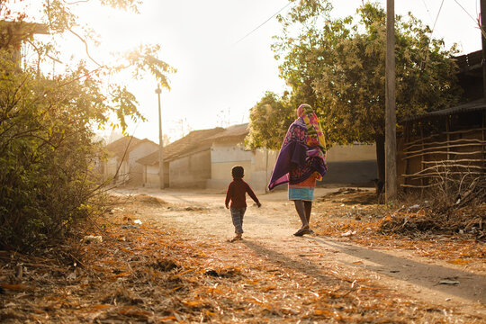 Child and father are walking together on a village path at dawn