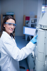 Female lab technician pressing panel to start test, generating animated charts on monitor