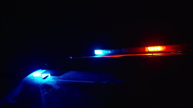Macro view of police siren lights glowing in red and blue at night with soft focus and strong color contrast creating dramatic cinematic atmosphere