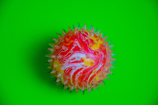 Colorful round object on bright green surface with spikes and swirls, squish