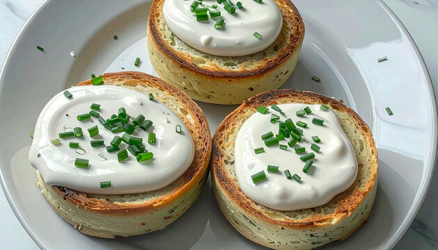 Toasted bread rounds topped with cream cheese and fresh chives on a white plate