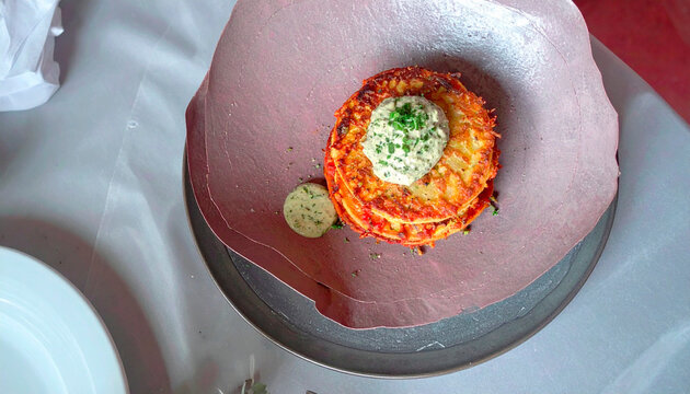 Crispy savory pastry stack with cherry tomatoes and herbs served with green pesto sauce on grey plate
