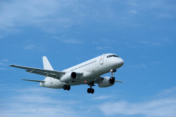 Fototapeta premium Detailed Close-up of Commercial Airplane Landing under Clear Blue Sky with Scattered Clouds.