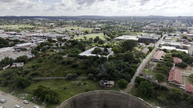 Drone flies over one of the power station towers and heads over Queens Fort Military Museum as camera pans down on fort on partially cloudy afternoon in Bloemfontein, South Africa