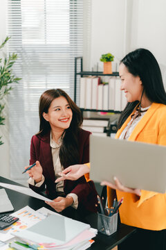 Two female colleagues are consulting and brainstorming. Two female accountants are preparing annual taxes together.