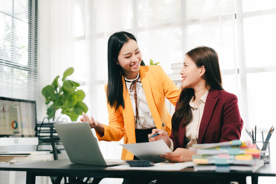 Two female colleagues are consulting and brainstorming. Two female accountants are preparing annual taxes together.